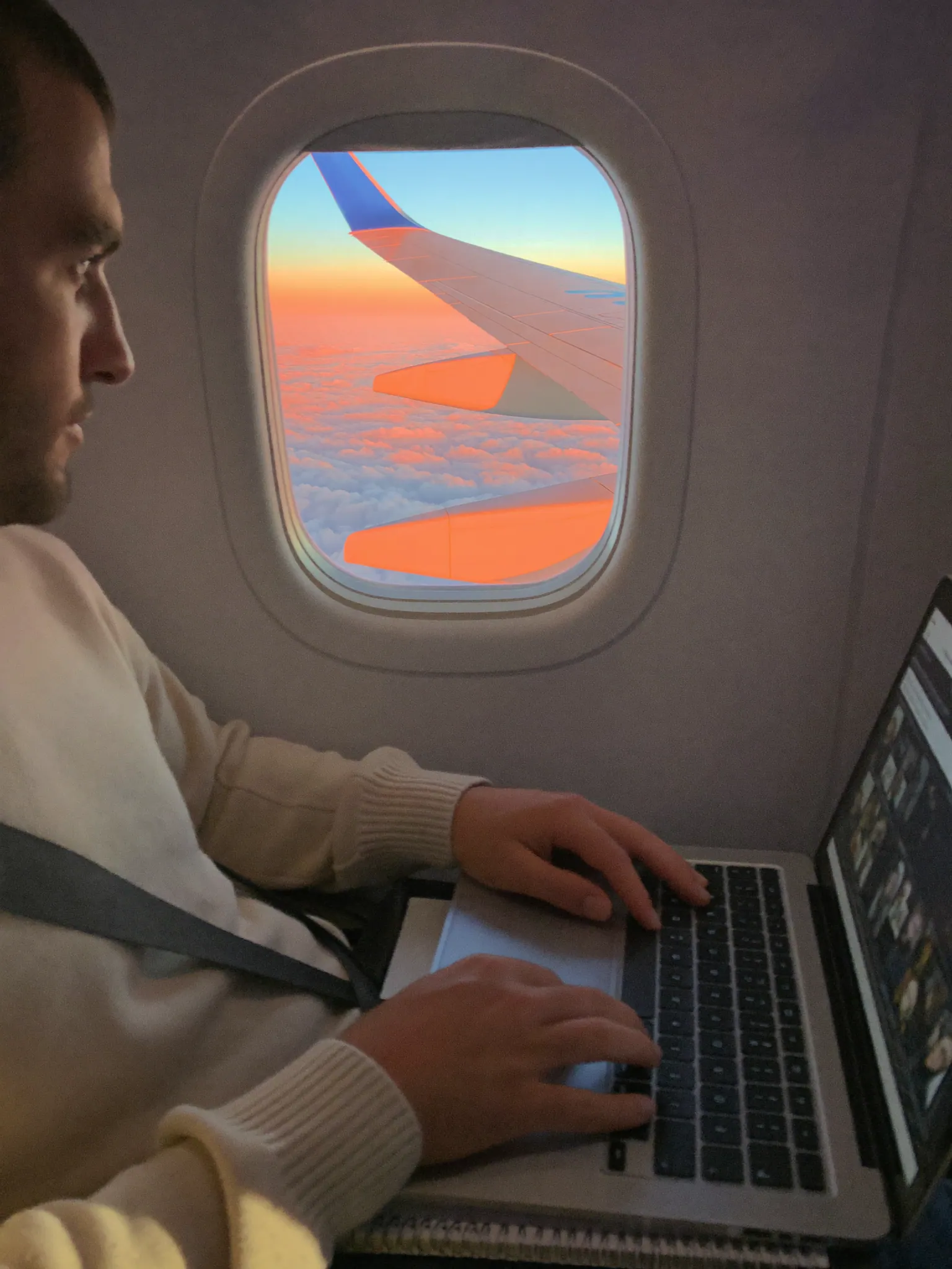 A creator working on a laptop in a private jet cabin at altitude