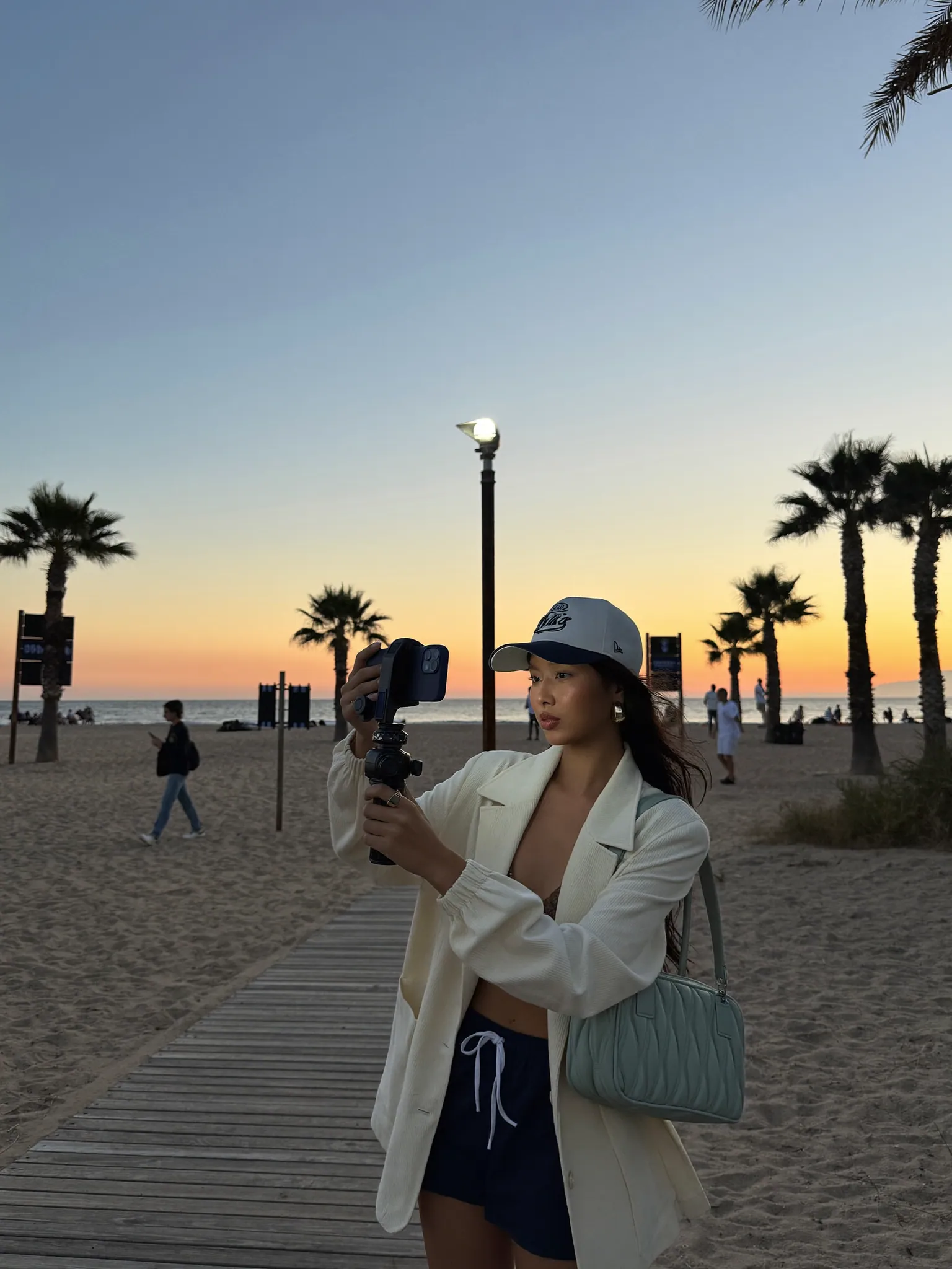 A creator filming UGC content on a Los Angeles boardwalk at sunset